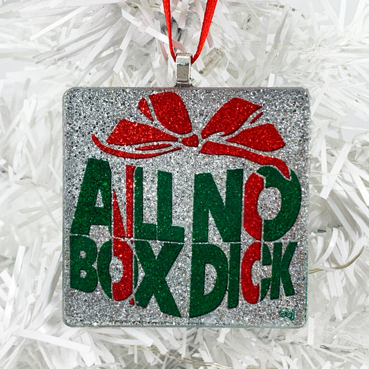 handmade glass ornament with "All Box No Dick" text-based gift-box-shaped graphic design in red and green on silver underlay