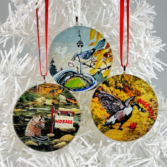 Three round handmade glass Christmas ornaments with images of Canadian Animals original paintings: No Sale Beaver, Blue Jays Love, Hiss Off Goose.