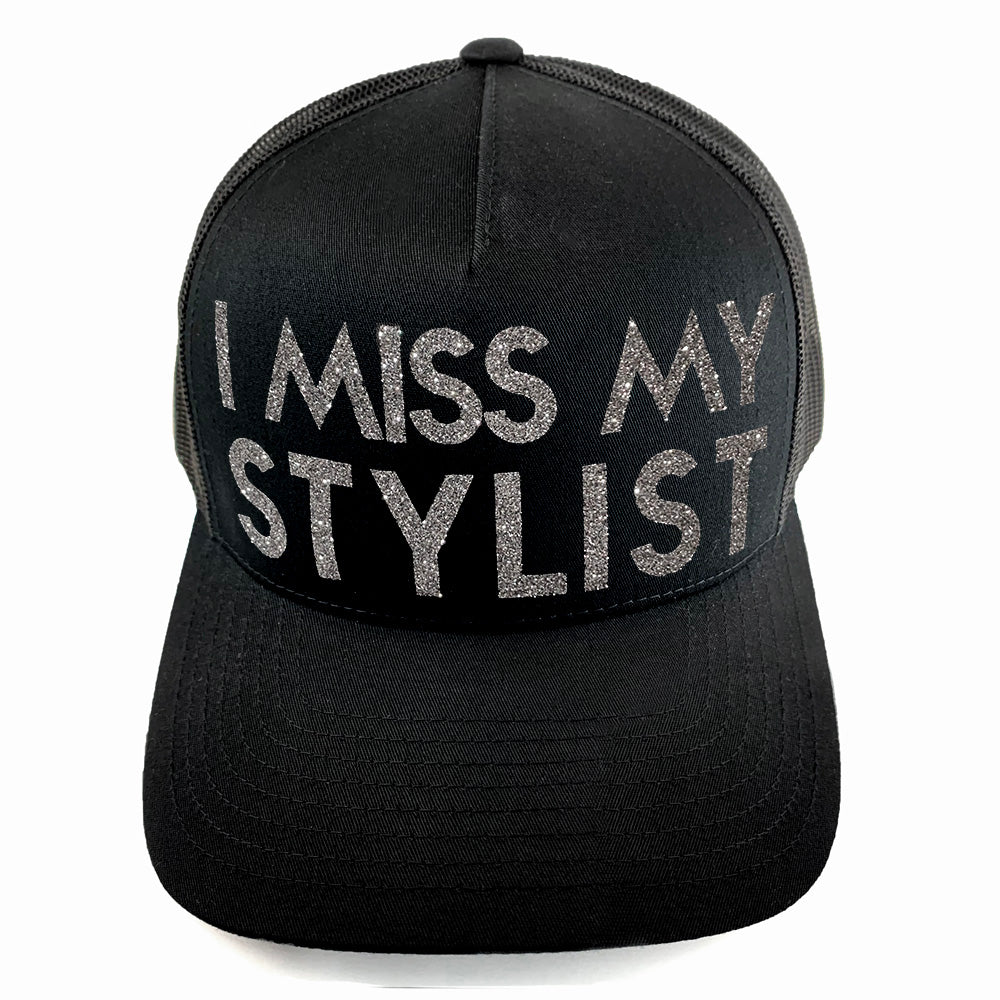 Classic black snapback hat with bold I Miss My Stylist text by BBJ / Glitter Garage. Silver glitter text. Front view.