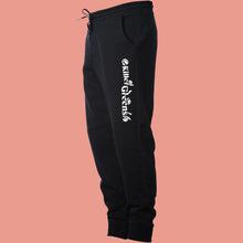 Load image into Gallery viewer, Killer Greens sweatpants. White long logo down left upper leg. Black unisex, ethically-made mid-weight fleece pants. Side view. by BBJ / Glitter Garage
