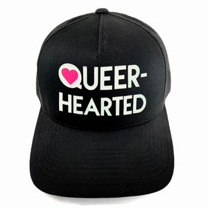 Classic black snapback hat with matte glow-in-the-dark and pink neon “Queer-hearted” detail by BBJ / Glitter Garage. Unisex style, breathable mesh back with matching plastic snap closure fits most. Front view.